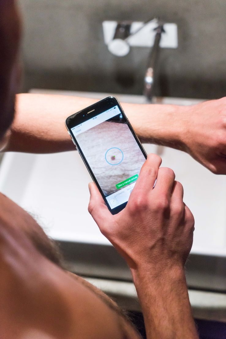 Exemple d'utilisation d'une application du domaine de la e-santé. Ici, un homme utilise son smartphone pour analyser un grain de beauté.